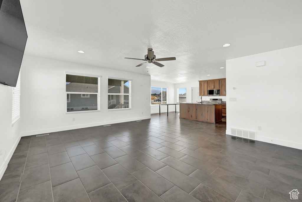 Unfurnished living room with ceiling fan and dark tile patterned flooring