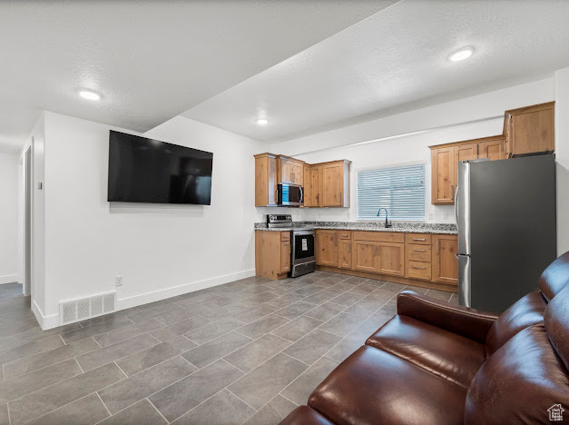 Kitchen with a textured ceiling, stainless steel appliances, sink, and tile patterned floors