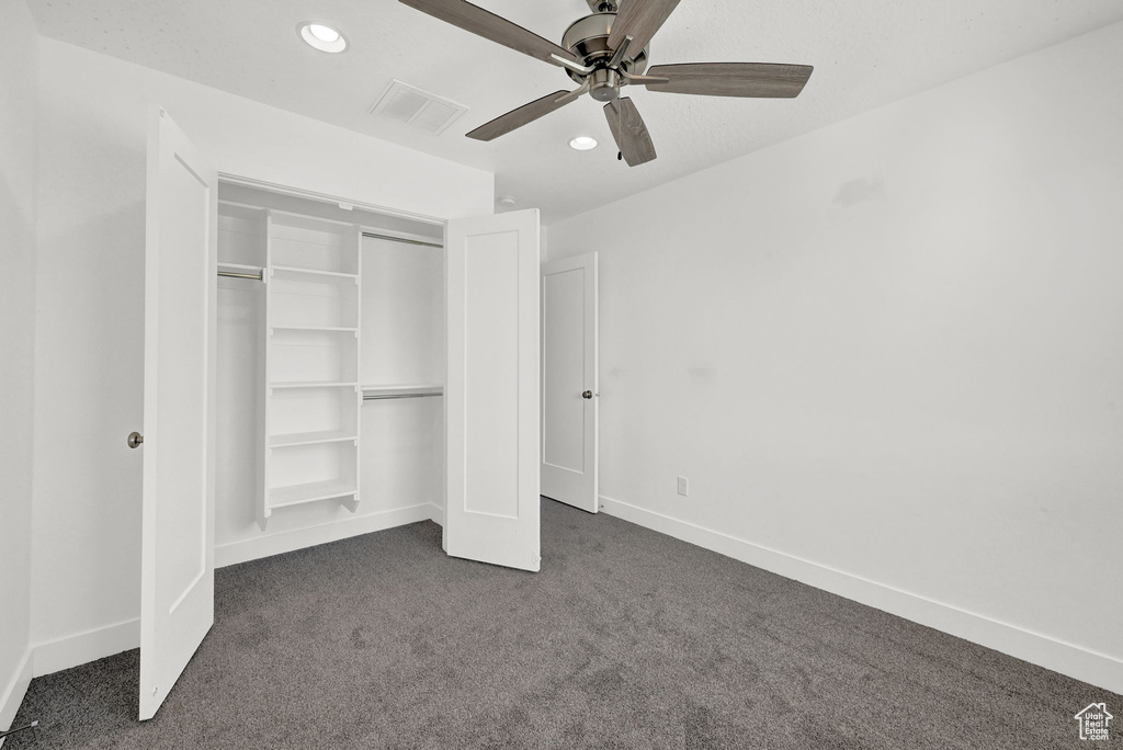 Unfurnished bedroom with dark carpet, a closet, and ceiling fan