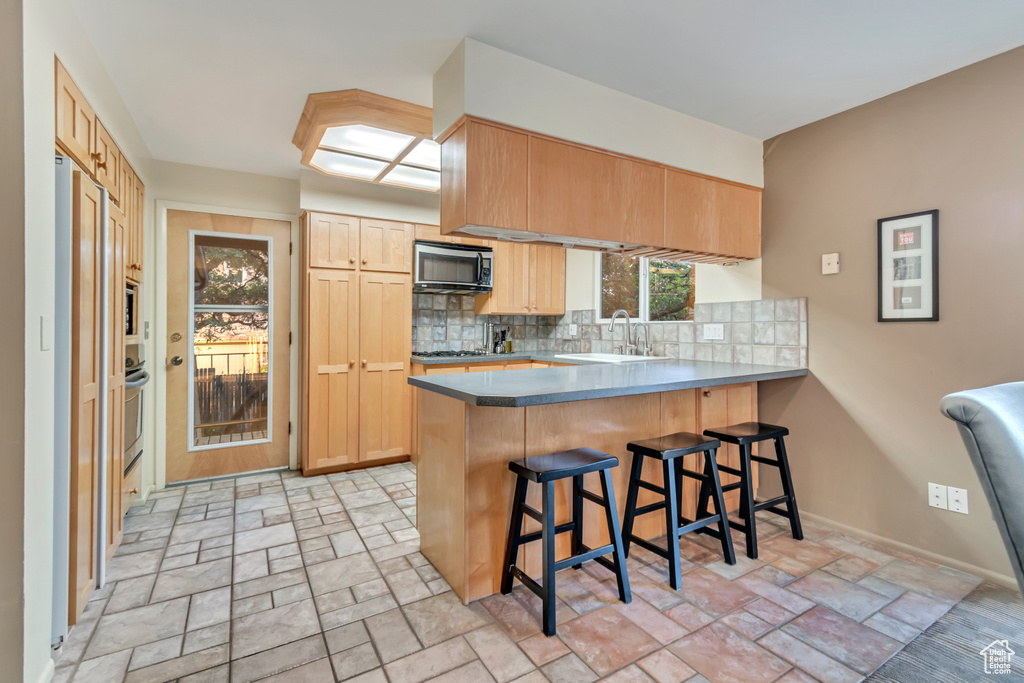 Kitchen with kitchen peninsula, appliances with stainless steel finishes, plenty of natural light, and sink