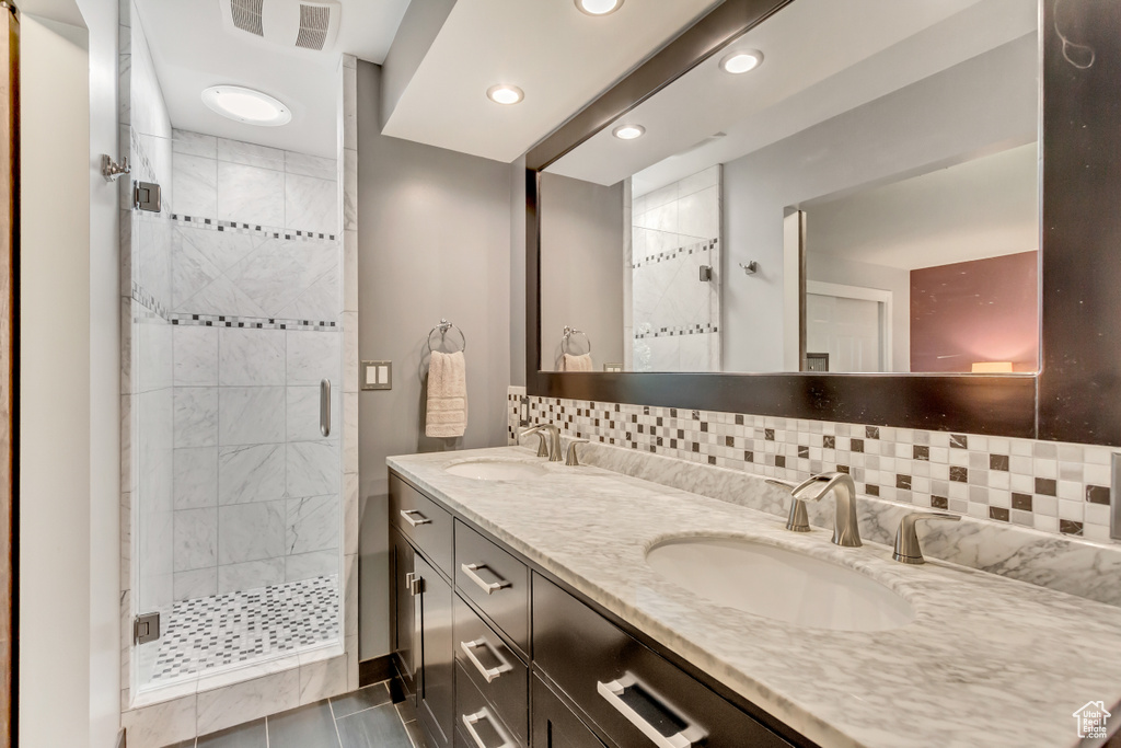 Bathroom featuring backsplash, vanity, and a shower with shower door