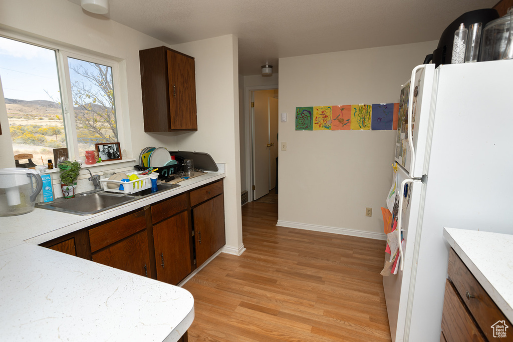 Kitchen with white refrigerator, sink, and light hardwood / wood-style flooring