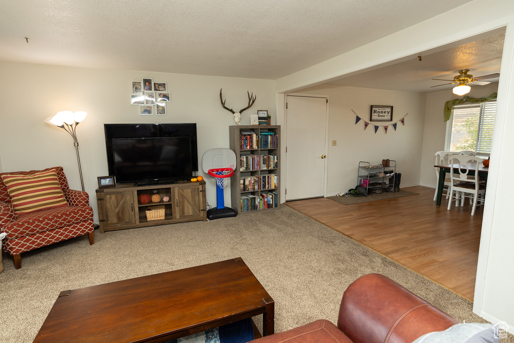 Living room featuring ceiling fan, hardwood / wood-style flooring, and a textured ceiling