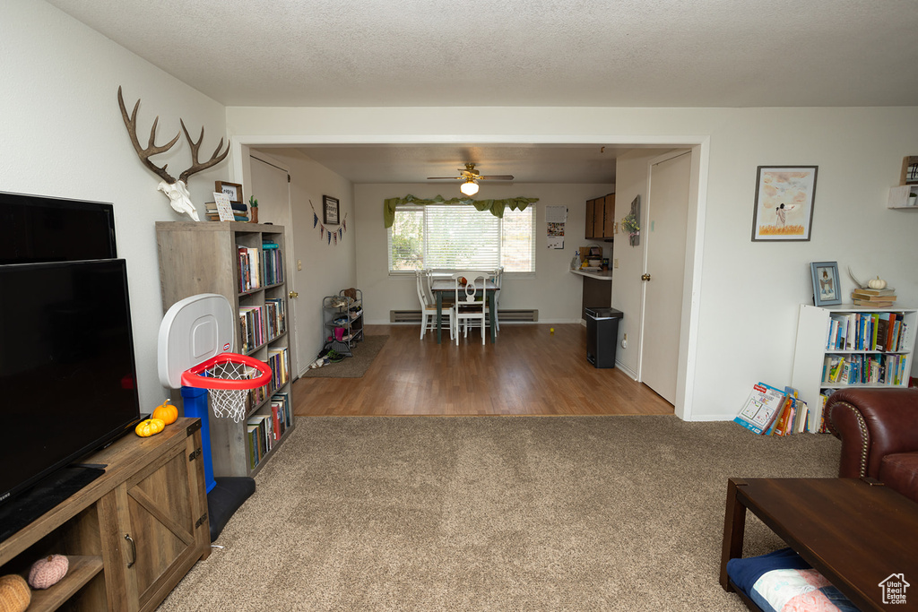 Living room with ceiling fan, hardwood / wood-style floors, and a textured ceiling