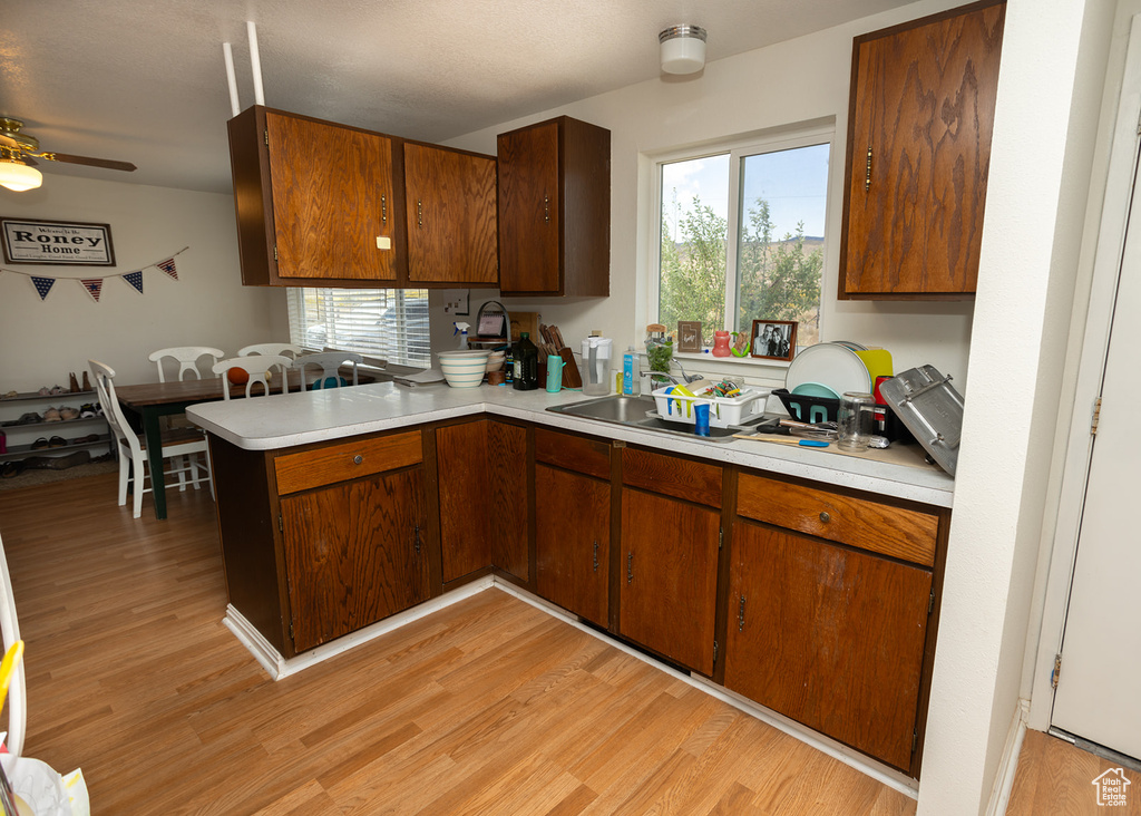 Kitchen with ceiling fan, light hardwood / wood-style flooring, and kitchen peninsula