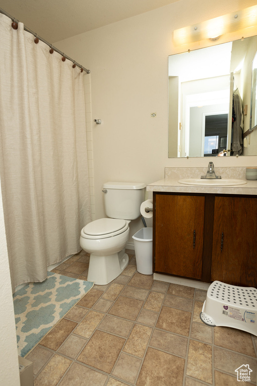 Bathroom with vanity, tile patterned floors, toilet, and curtained shower