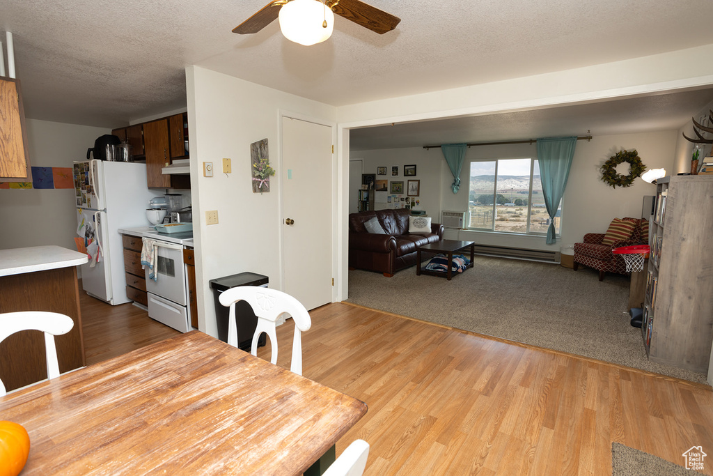 Dining room with light wood-type flooring, ceiling fan, and a textured ceiling