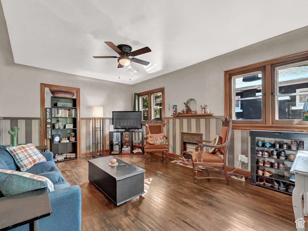 Living room with ceiling fan, dark hardwood / wood-style floors, a fireplace, and a healthy amount of sunlight