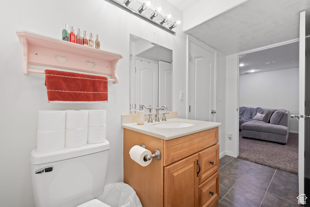 Bathroom with tile patterned flooring, a textured ceiling, vanity, and toilet