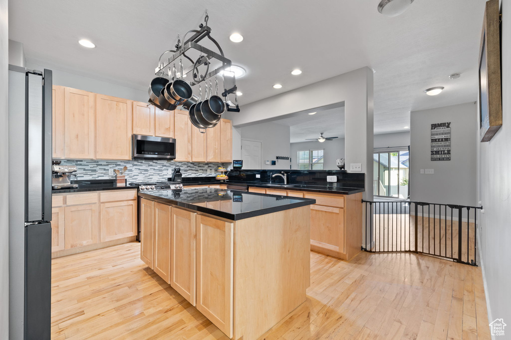 Kitchen with a kitchen island, light brown cabinets, stainless steel appliances, and light hardwood / wood-style flooring