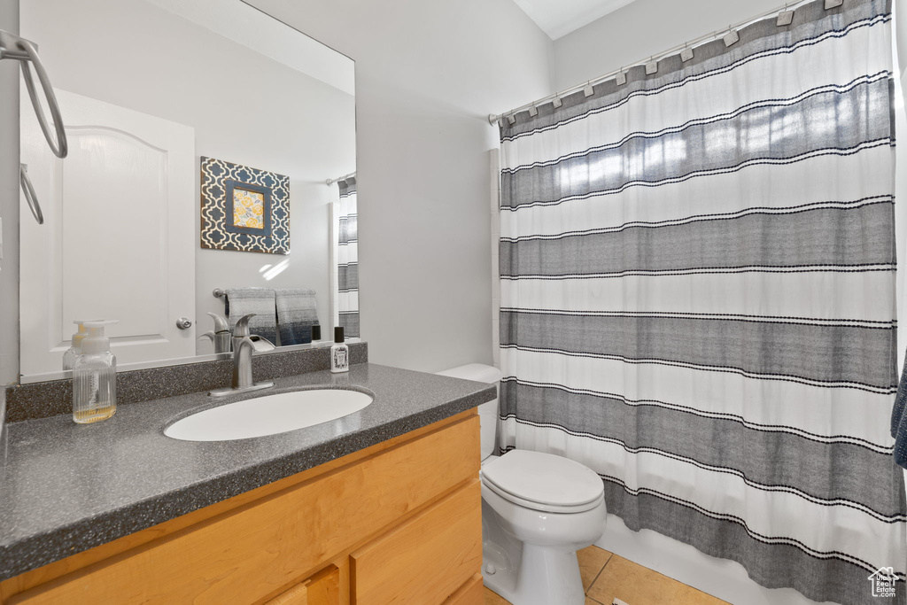 Bathroom featuring tile patterned flooring, a shower with shower curtain, vanity, and toilet