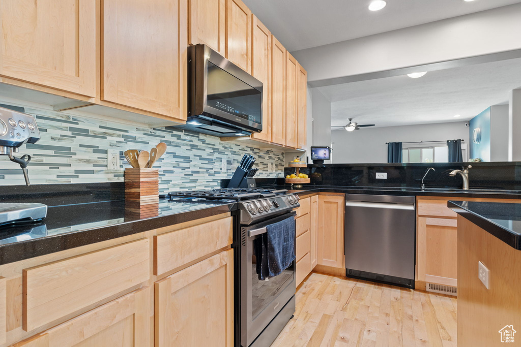 Kitchen with light brown cabinets, appliances with stainless steel finishes, sink, and light wood-type flooring