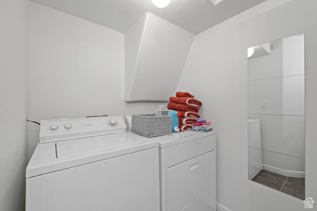 Laundry room featuring washing machine and dryer, tile patterned floors, and a textured ceiling