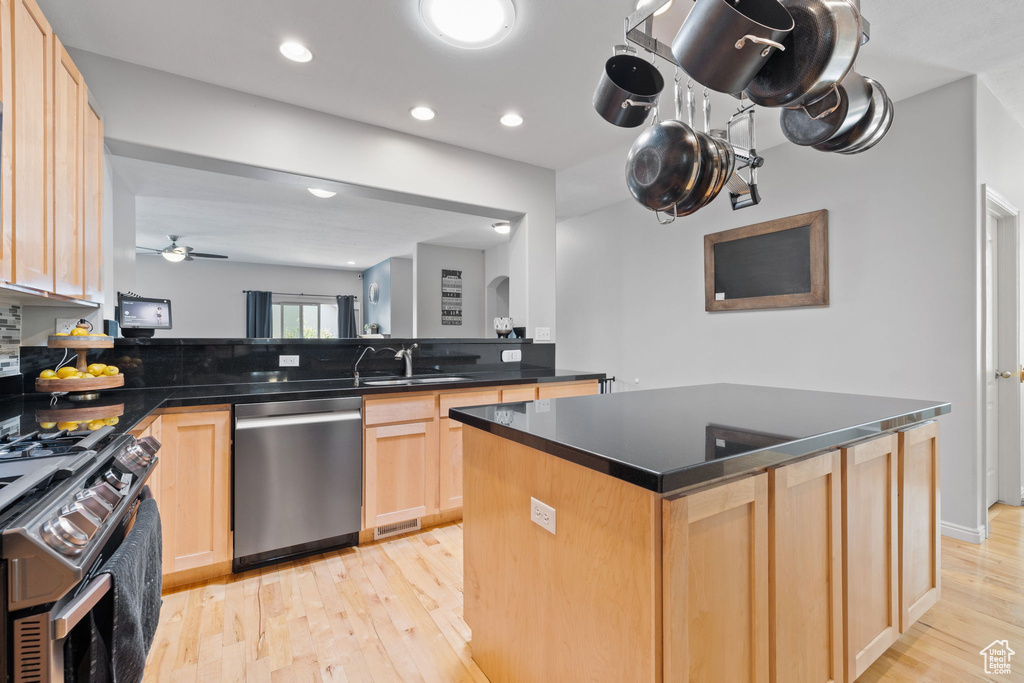 Kitchen with kitchen peninsula, a kitchen island, light hardwood / wood-style flooring, stainless steel appliances, and light brown cabinetry