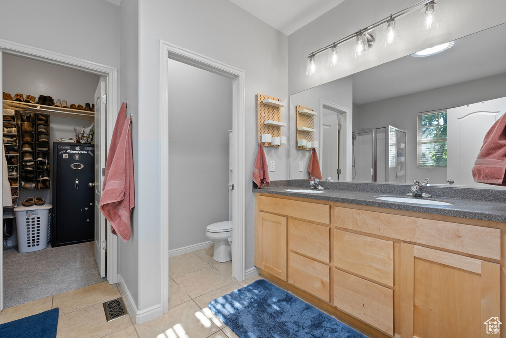 Bathroom featuring tile patterned floors, toilet, vanity, and a shower with shower door