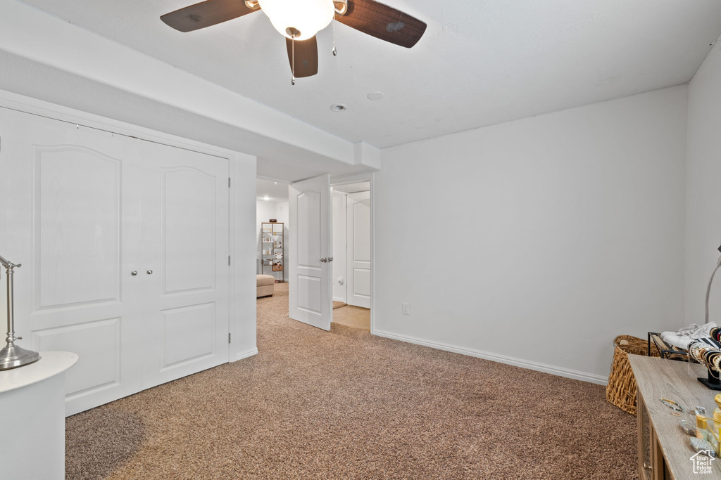 Unfurnished bedroom featuring ceiling fan, a closet, and light carpet