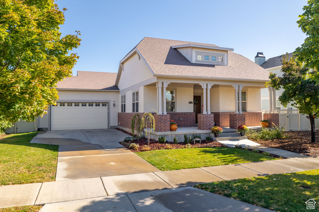 View of front of house with a garage, a front lawn, and covered porch