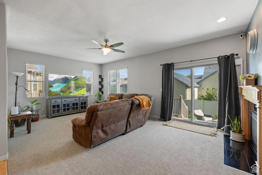 Living room featuring a fireplace, carpet, and ceiling fan