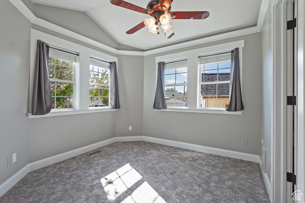 Carpeted spare room featuring ceiling fan, lofted ceiling, and ornamental molding