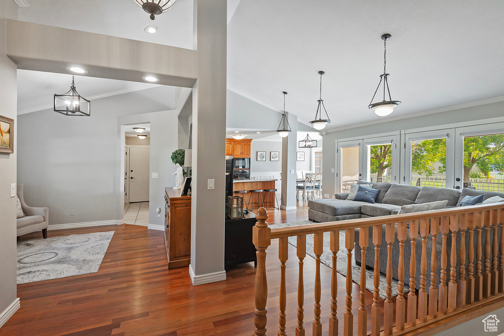 Living room featuring lofted ceiling, french doors, a notable chandelier, crown molding, and hardwood / wood-style floors