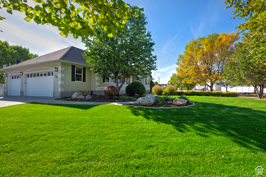 View of front facade featuring a garage and a front lawn