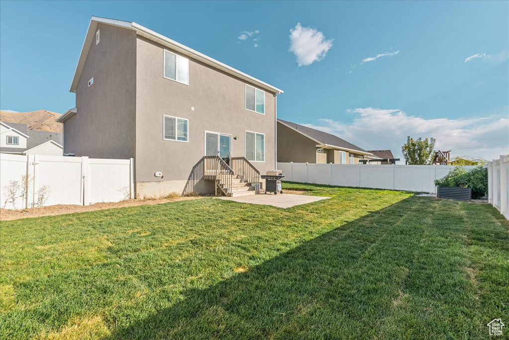 Back of house featuring a lawn and a patio area