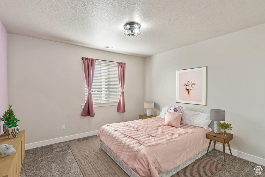 Bedroom with a textured ceiling and carpet flooring