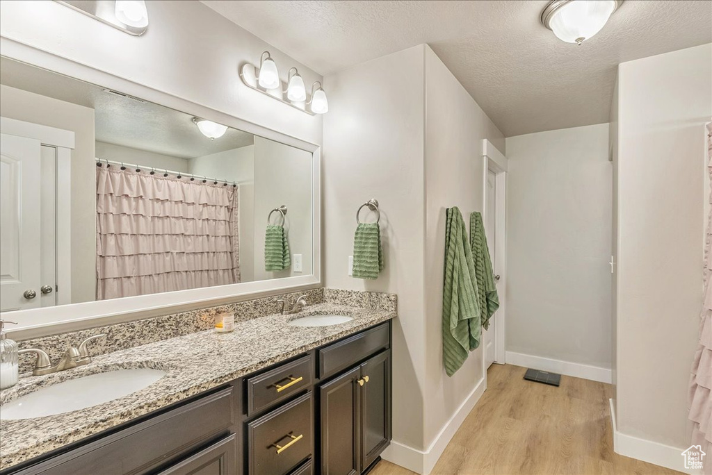 Bathroom with hardwood / wood-style flooring, vanity, and a textured ceiling