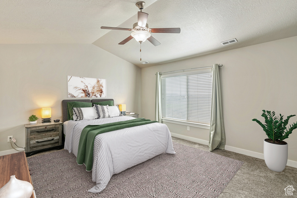 Carpeted bedroom featuring ceiling fan and vaulted ceiling