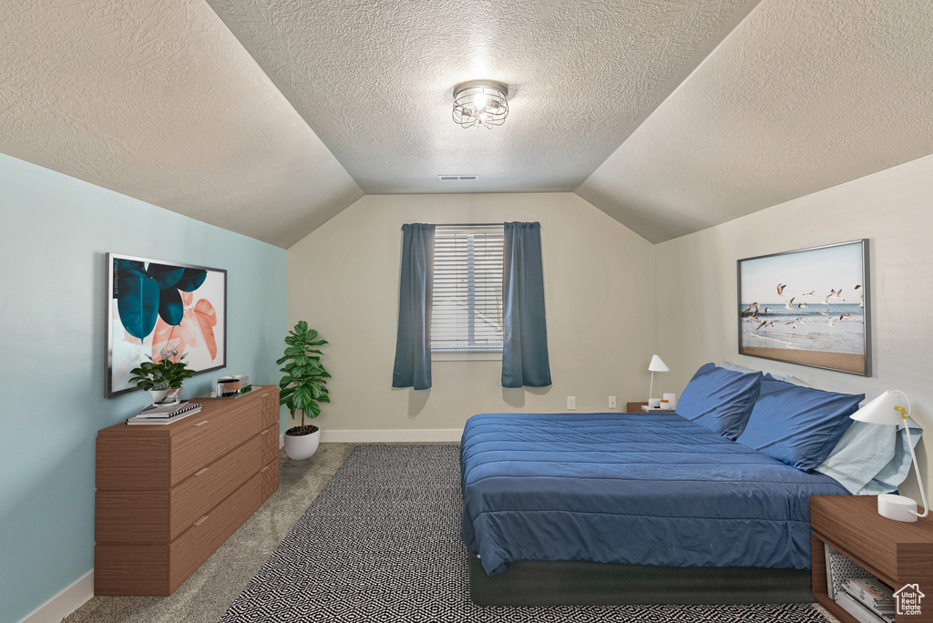 Bedroom featuring a textured ceiling, lofted ceiling, and carpet