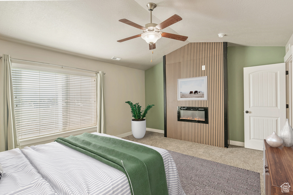 Bedroom featuring a textured ceiling, vaulted ceiling, carpet flooring, and ceiling fan