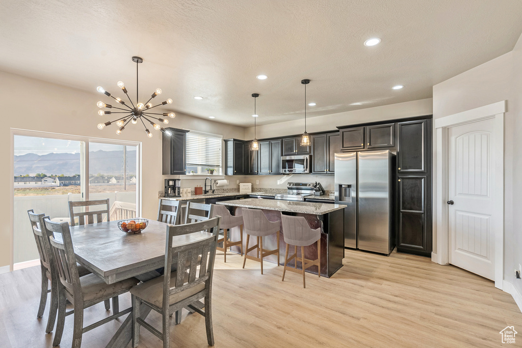 Dining area featuring a textured ceiling, light wood-type flooring, sink, and a chandelier