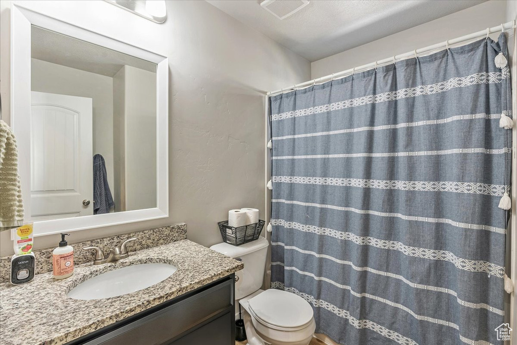 Bathroom featuring vanity, toilet, and curtained shower