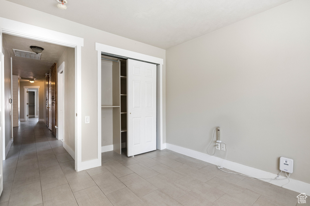 Unfurnished bedroom featuring a closet and light tile patterned floors