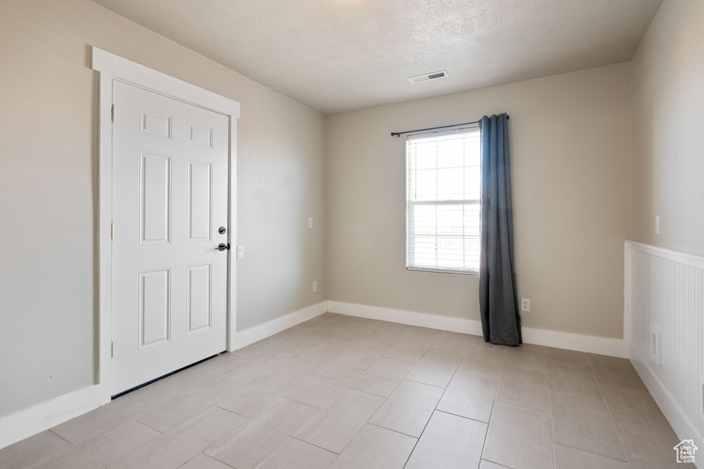 Empty room featuring a textured ceiling and light tile patterned floors