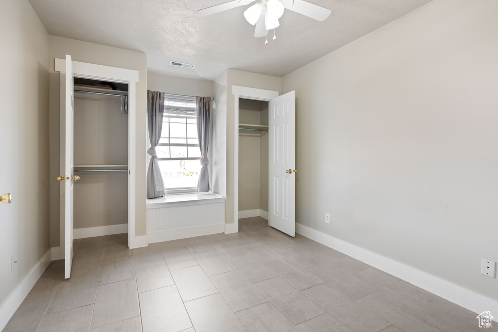 Unfurnished bedroom with ceiling fan and light tile patterned floors