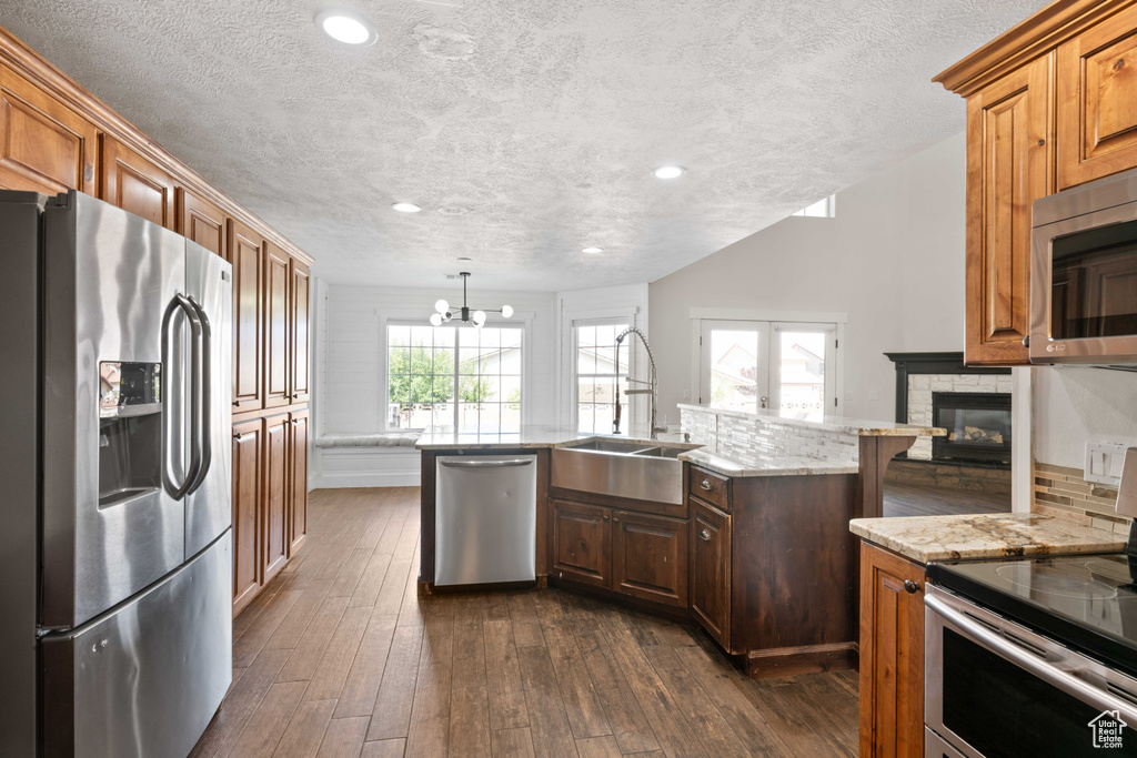 Kitchen with appliances with stainless steel finishes, a wealth of natural light, sink, and dark hardwood / wood-style floors