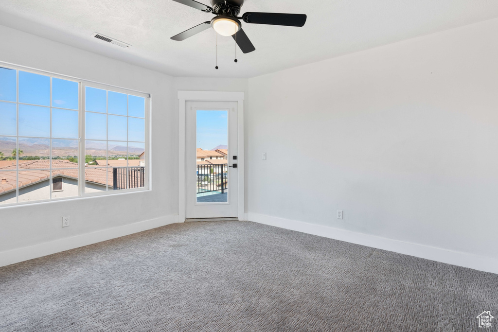 Carpeted empty room featuring ceiling fan