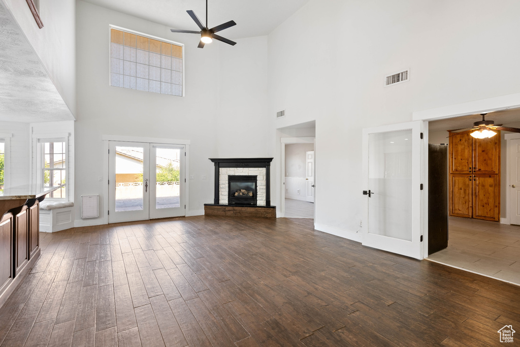 Unfurnished living room featuring ceiling fan, dark wood-type flooring, a towering ceiling, and french doors