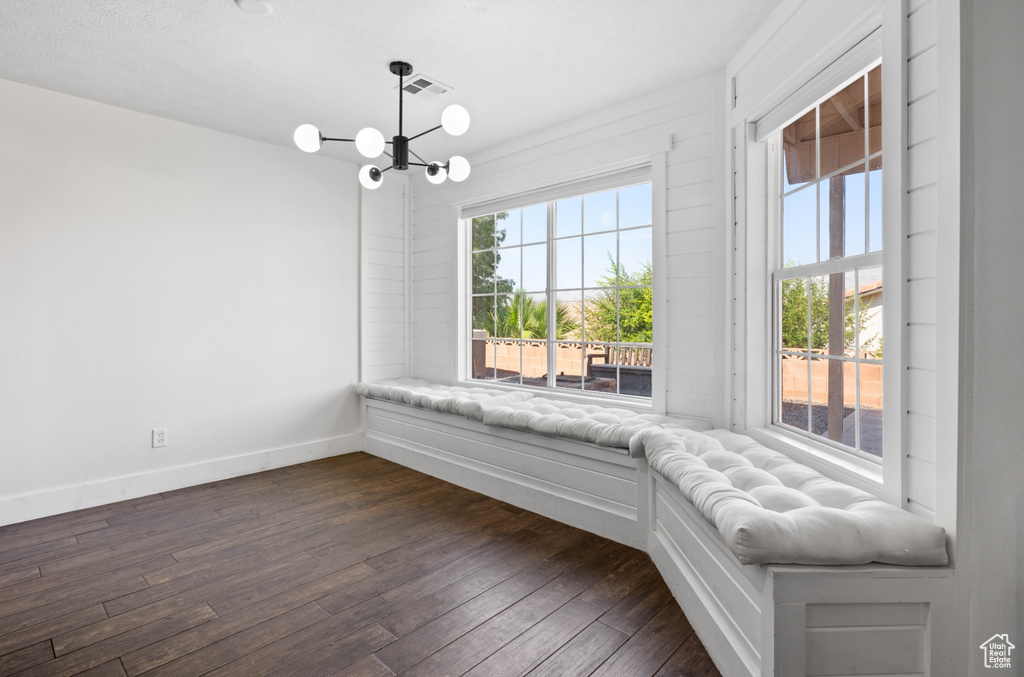 Unfurnished room with a notable chandelier and dark wood-type flooring