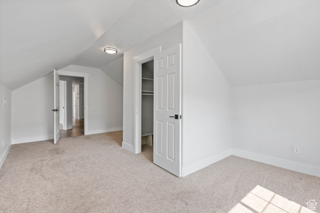 Additional living space featuring lofted ceiling and light colored carpet