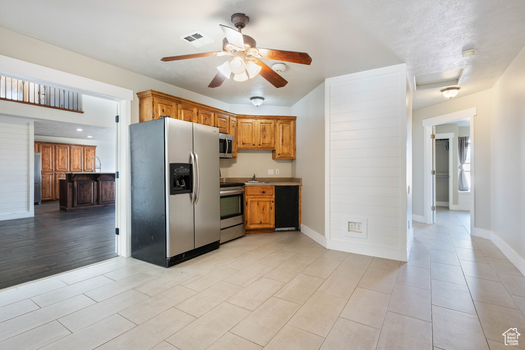 Kitchen with appliances with stainless steel finishes, light hardwood / wood-style flooring, and ceiling fan