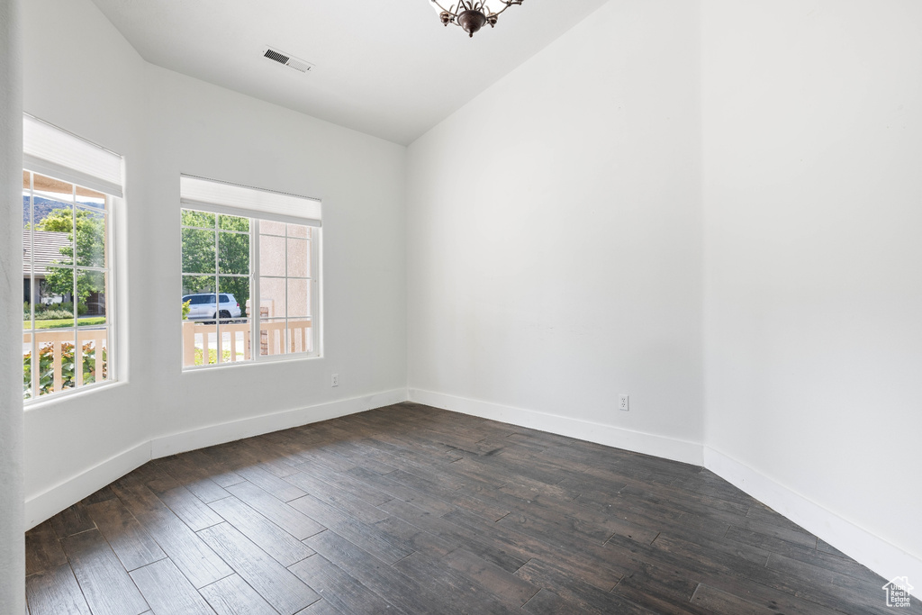 Empty room with lofted ceiling and dark hardwood / wood-style flooring