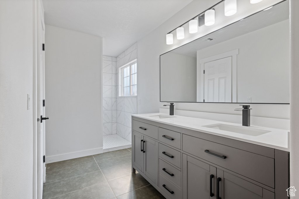 Bathroom with a tile shower, tile patterned floors, and vanity