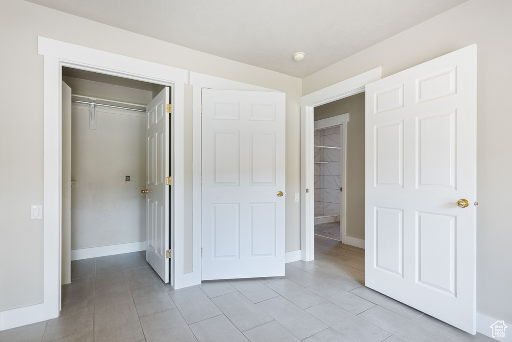 Unfurnished bedroom with a closet and light tile patterned floors