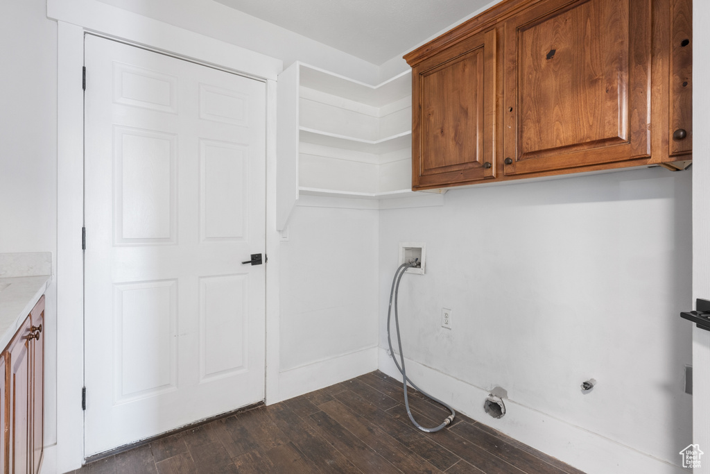 Clothes washing area featuring dark wood-type flooring, washer hookup, and cabinets