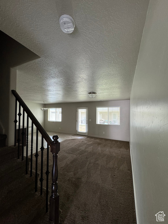 Interior space featuring a textured ceiling and dark colored carpet