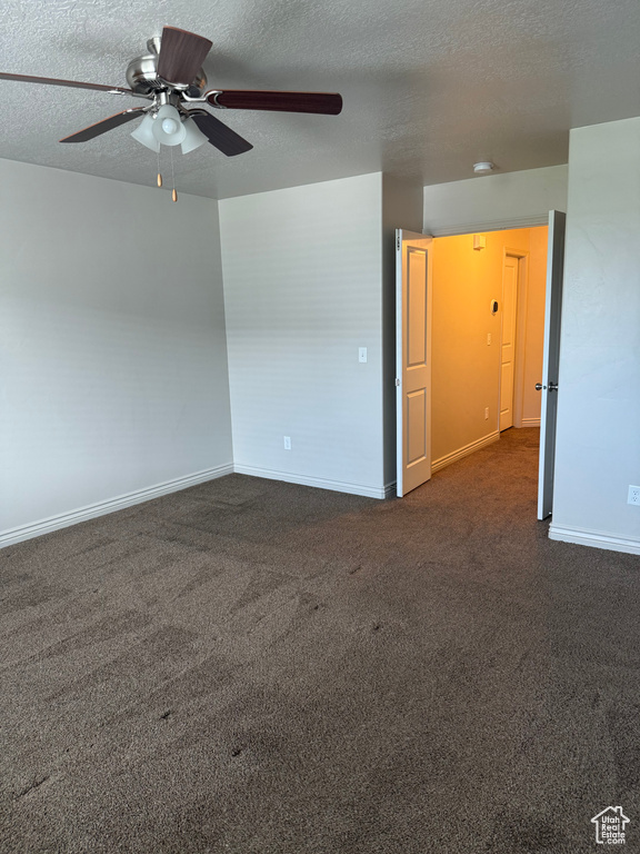 Carpeted empty room featuring ceiling fan and a textured ceiling