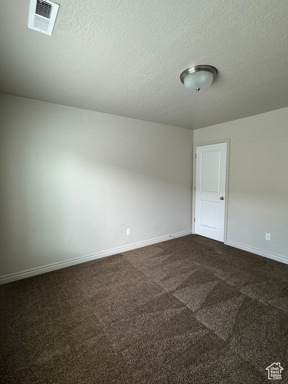 Unfurnished room featuring dark carpet and a textured ceiling