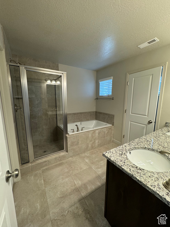 Bathroom featuring shower with separate bathtub, vanity, and a textured ceiling
